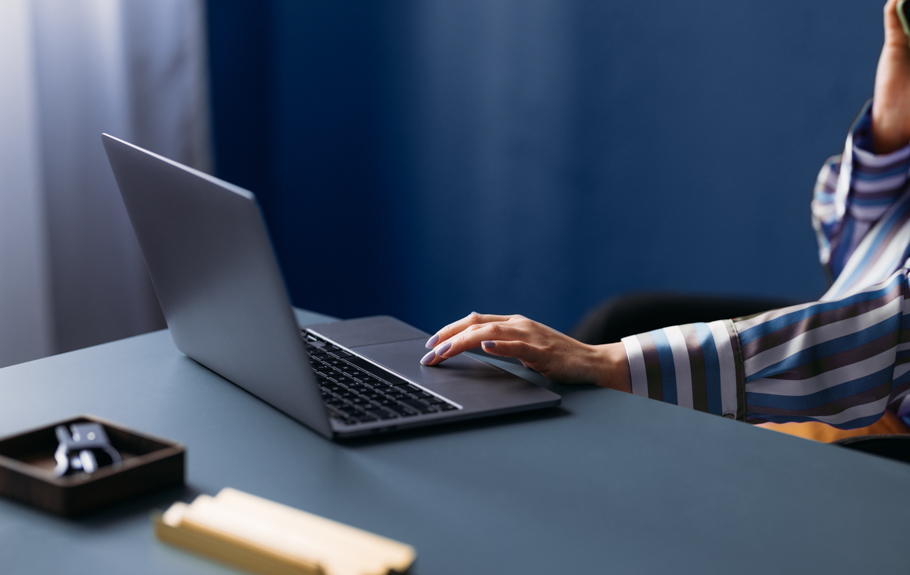 Ein Laptop liegt auf einem Tisch mit blauem Hintergrund. 